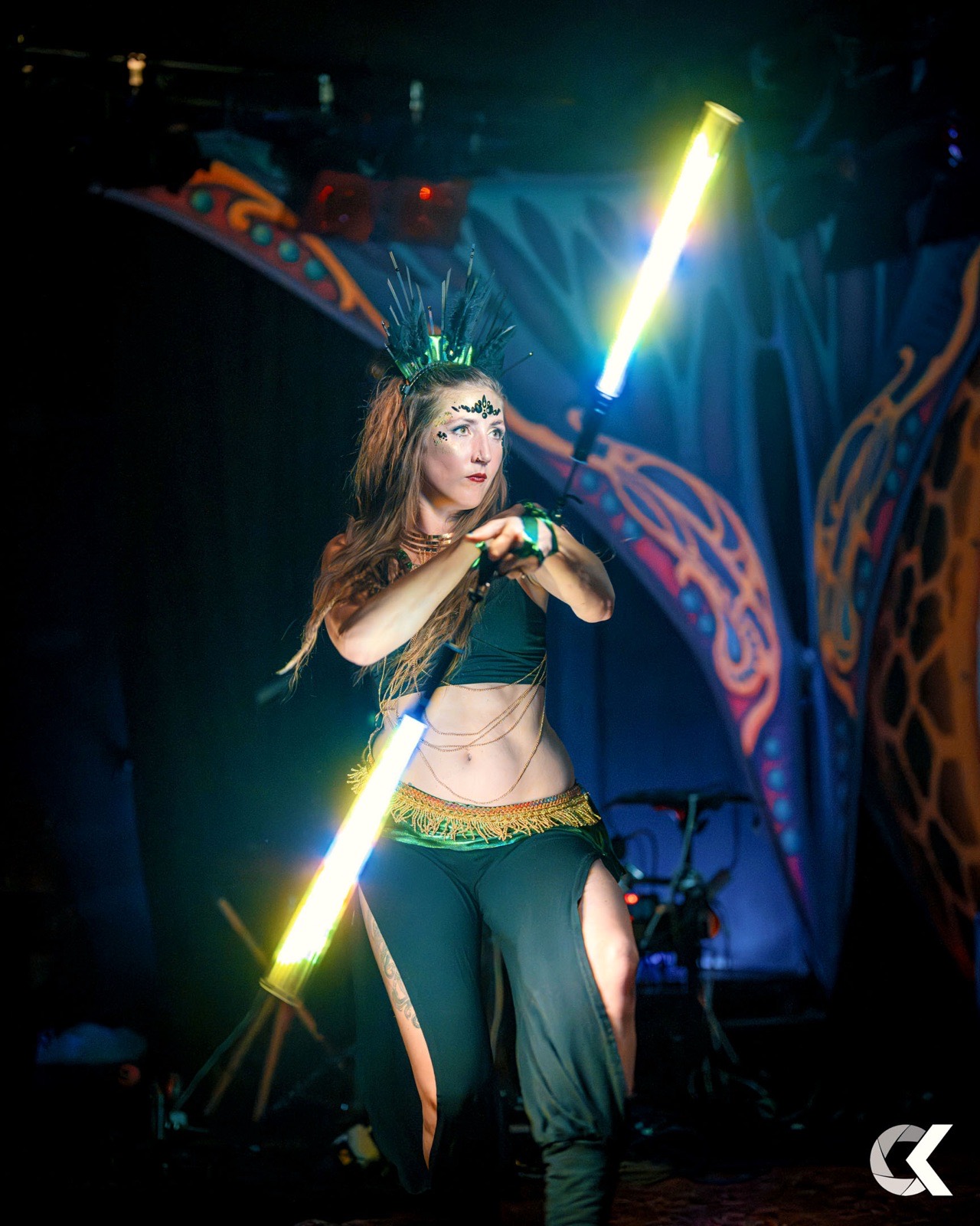 Performer spinning a glowing LED staff on a darkened stage