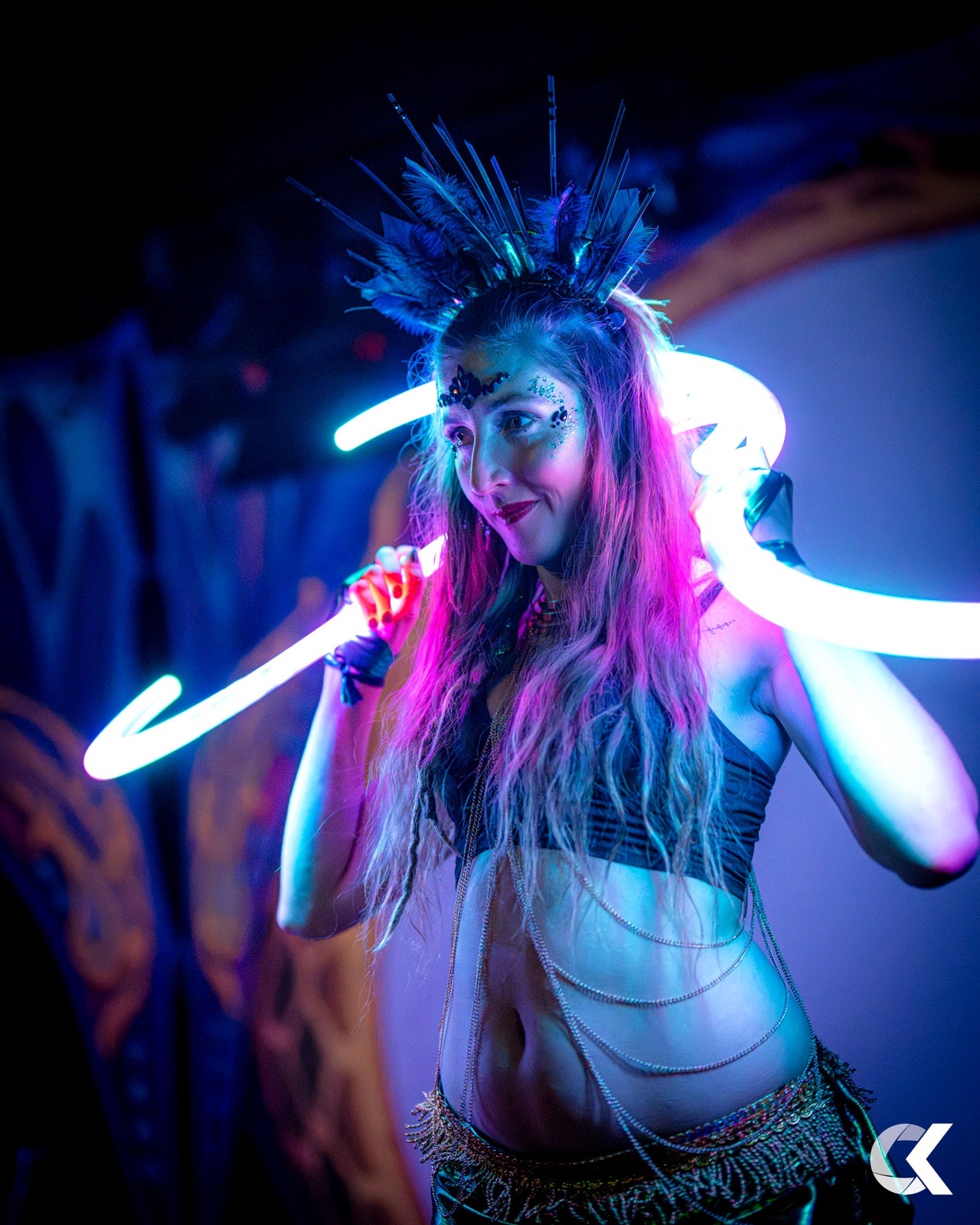 Performer with feather crown and glowing LED props on stage