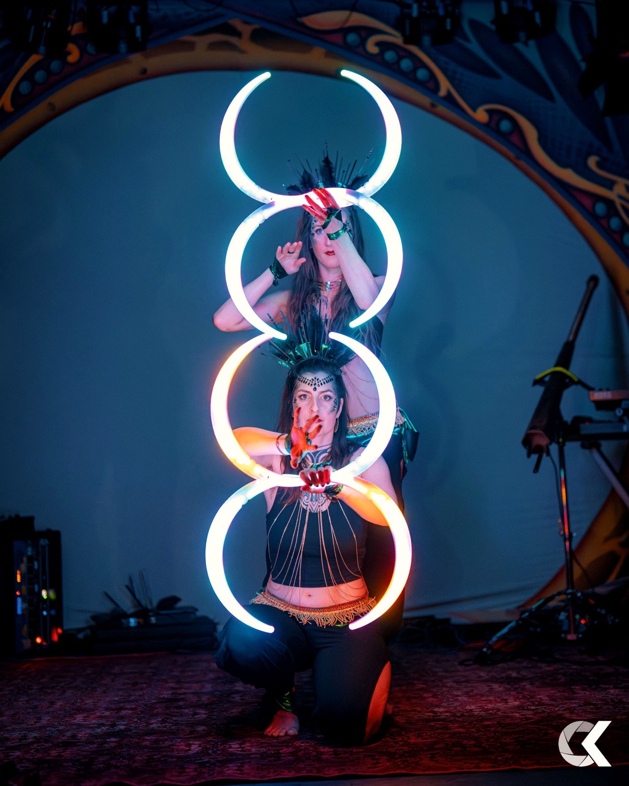 Two performers with glowing LED hoops stacked in bright circles