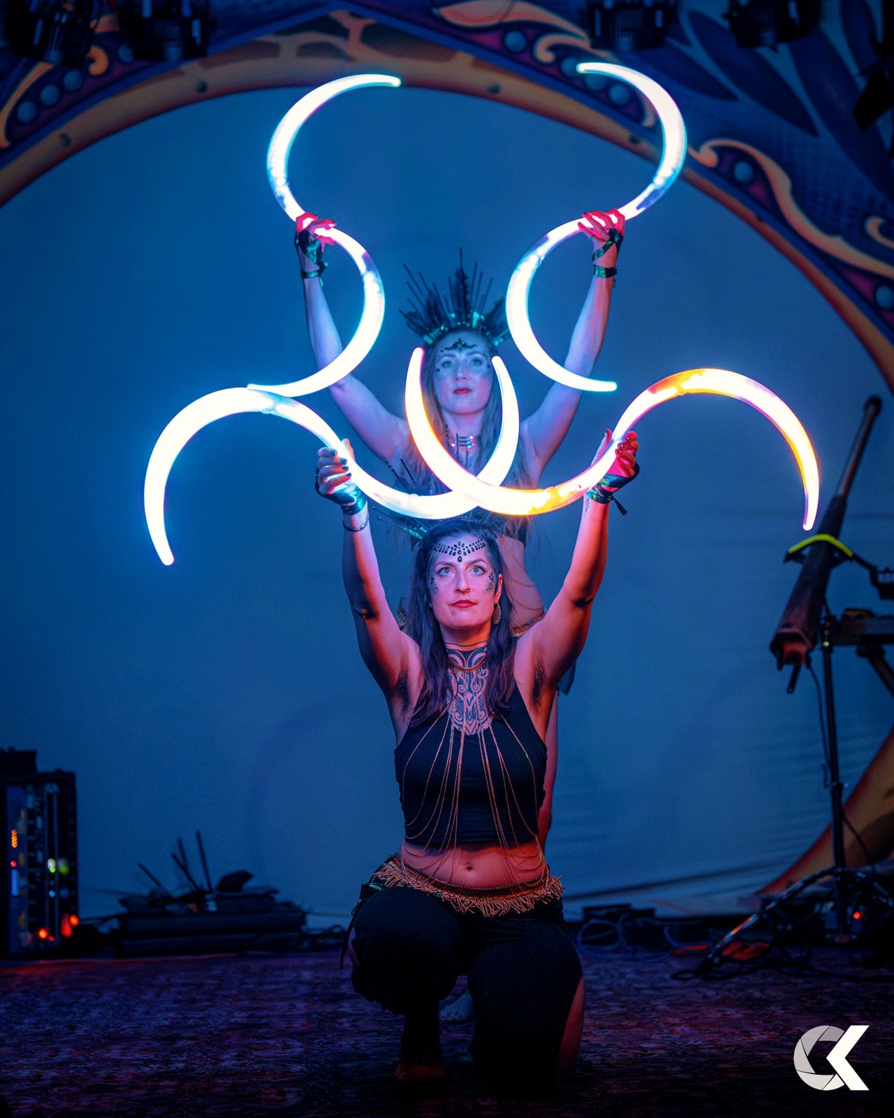 Two performers with six glowing LED crescents under a blue tent dome